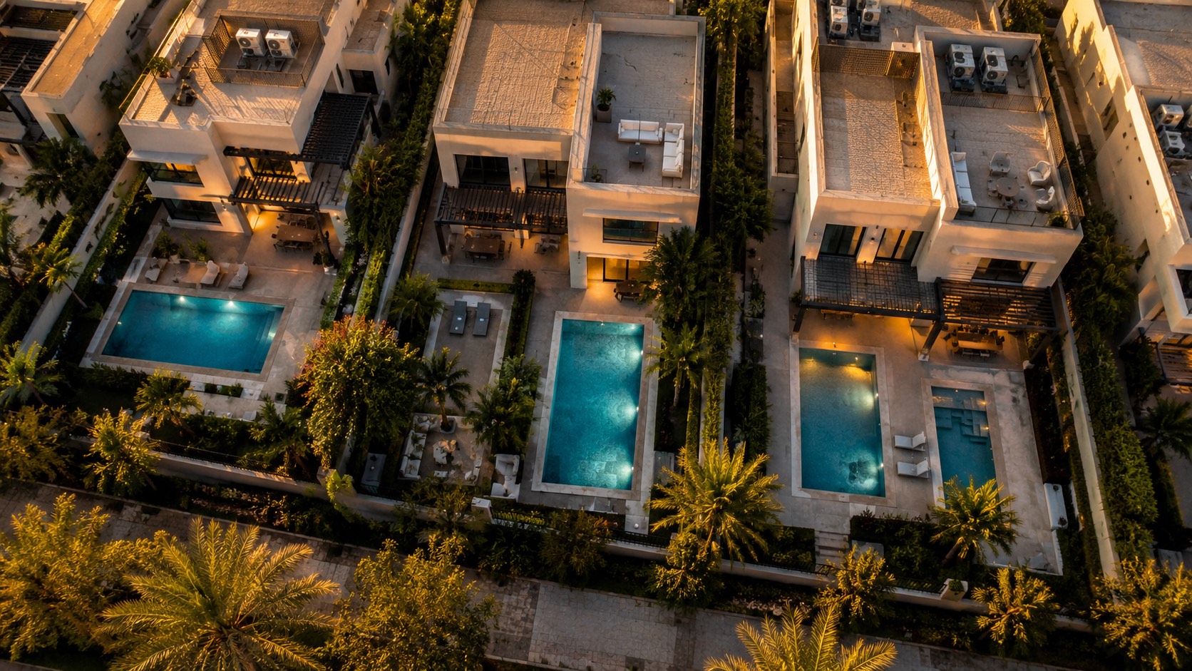 Row of Dubai villa swimming pools glowing at golden hour, seen from above